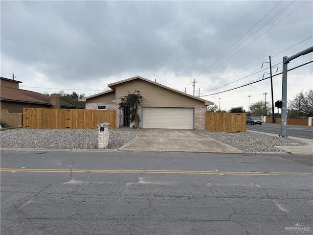 view of front of home featuring a garage, fence, concrete driveway, and brick siding