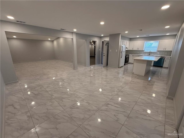 interior space featuring open floor plan, light countertops, freestanding refrigerator, decorative backsplash, and dishwasher