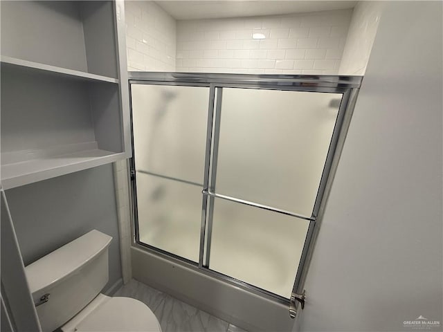 bathroom featuring toilet and combined bath / shower with glass door