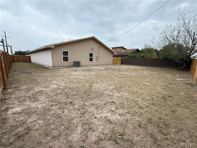 back of property with a fenced backyard and central air condition unit