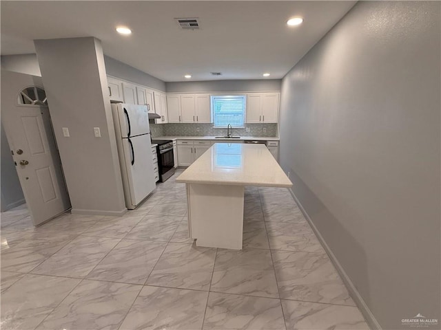 kitchen featuring visible vents, marble finish floor, freestanding refrigerator, and stainless steel electric stove