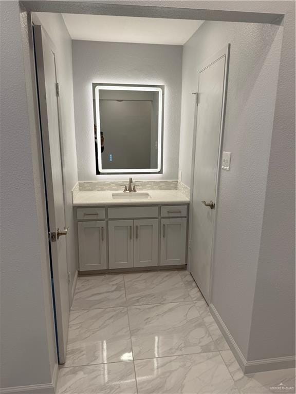 bathroom with marble finish floor, baseboards, and vanity