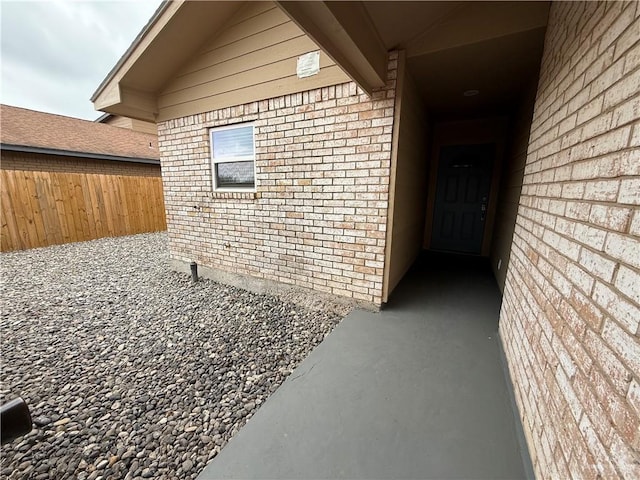 doorway to property with brick siding and fence