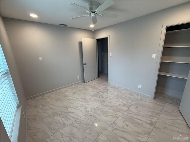 unfurnished bedroom featuring a walk in closet, marble finish floor, visible vents, a ceiling fan, and baseboards