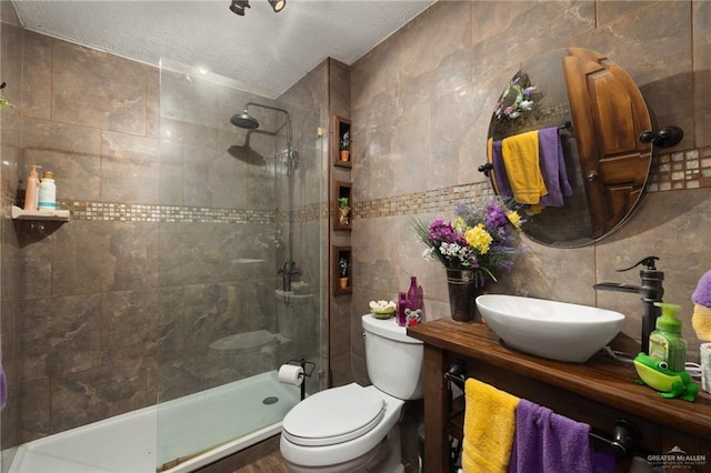 2820 Joan Dr, Edinburg, TX 78541 - full bathroom featuring tile walls, tiled shower, toilet, vanity, and a textured ceiling