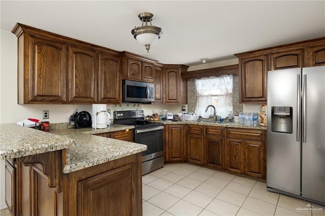 kitchen featuring stainless steel appliances, light stone countertops, sink, and light tile patterned floors