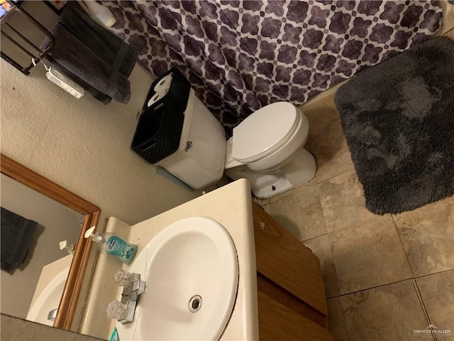 bathroom featuring tile patterned flooring, toilet, and a sink