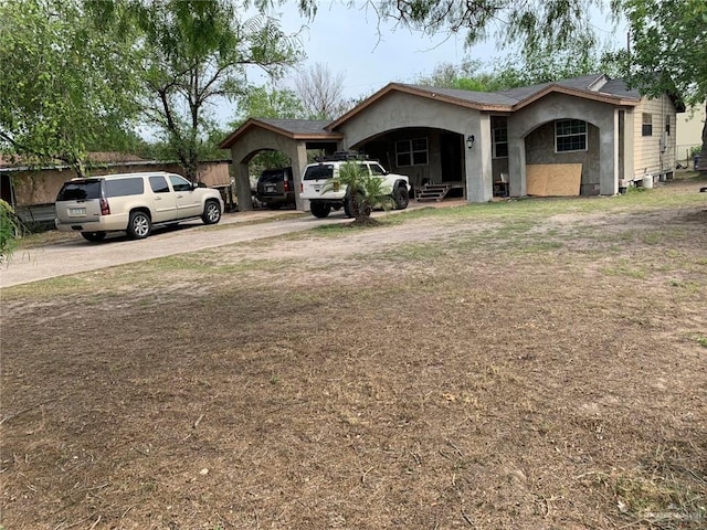 view of front of house with stucco siding, driveway, and a carport
