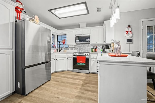 kitchen with white cabinets, a kitchen bar, kitchen peninsula, and appliances with stainless steel finishes