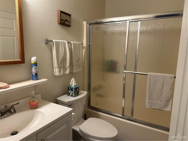 42 E Cherokee Dr, Harlingen, TX 78550 - full bathroom featuring bath / shower combo with glass door, toilet, vanity, and a textured wall