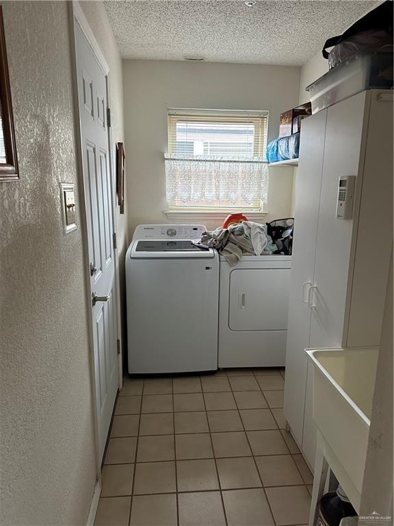 42 E Cherokee Dr, Harlingen, TX 78550 - laundry room with separate washer and dryer, light tile patterned floors, a textured ceiling, and a textured wall