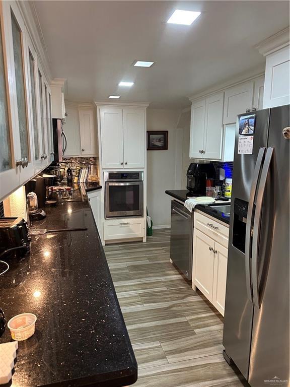 42 E Cherokee Dr, Harlingen, TX 78550 - kitchen featuring stainless steel appliances, white cabinetry, backsplash, and dark stone countertops