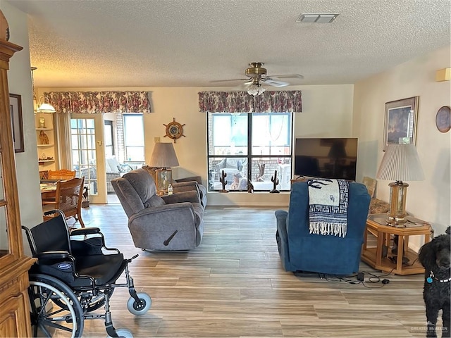 42 E Cherokee Dr, Harlingen, TX 78550 - living area featuring a textured ceiling, light wood-style floors, a ceiling fan, and plenty of natural light