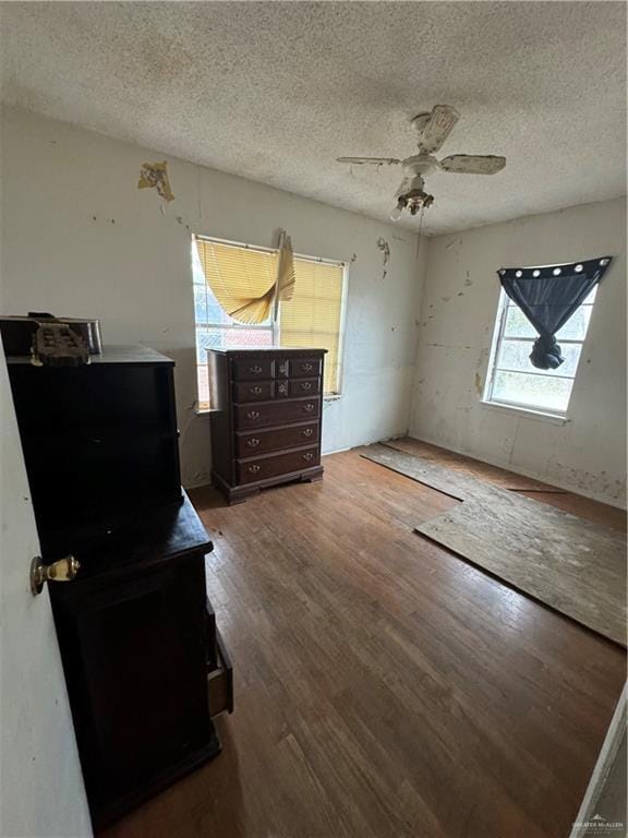 bedroom with a textured ceiling, hardwood / wood-style flooring, and ceiling fan