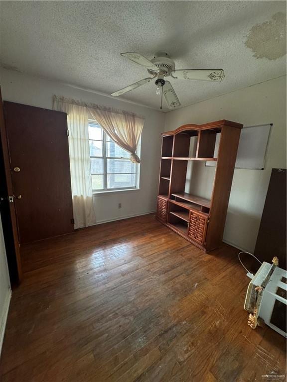 unfurnished living room featuring a textured ceiling, ceiling fan, and dark wood-type flooring