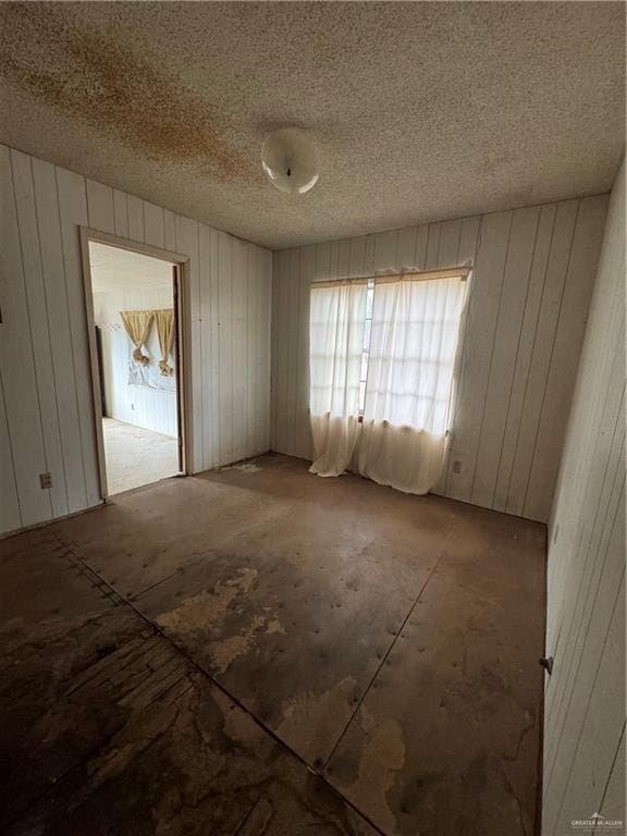 empty room featuring wood walls and a textured ceiling