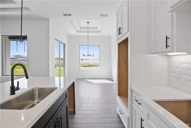 kitchen with light countertops, a tray ceiling, a sink, and visible vents