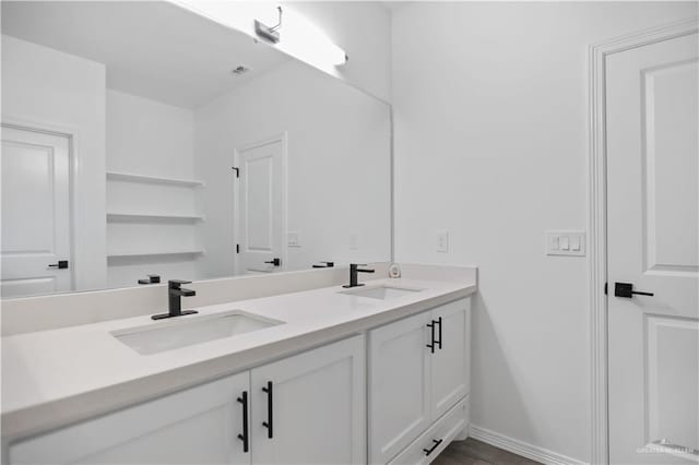 bathroom with a sink, baseboards, and double vanity