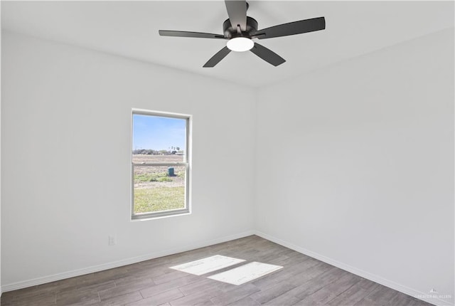 unfurnished room with wood finished floors, a ceiling fan, and baseboards