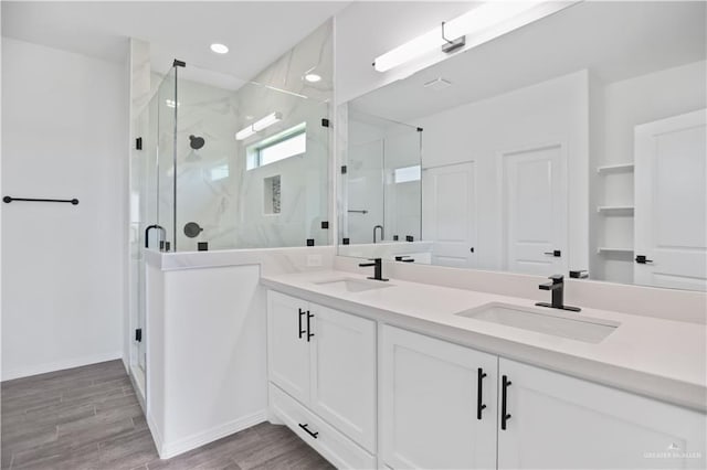 full bathroom with double vanity, a stall shower, wood tiled floor, and a sink