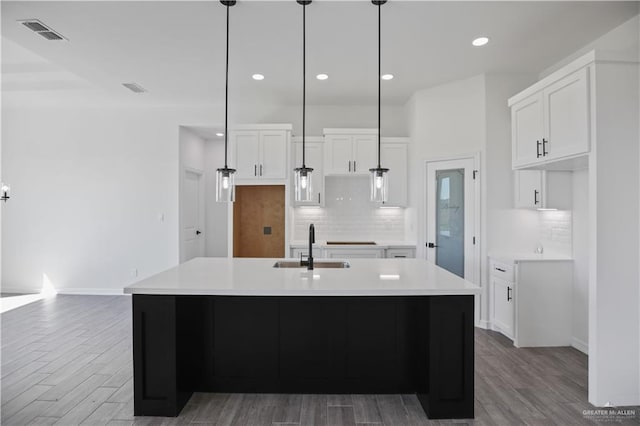 kitchen featuring wood finished floors, a sink, visible vents, and white cabinetry