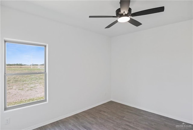 spare room with dark wood-style flooring, ceiling fan, and baseboards