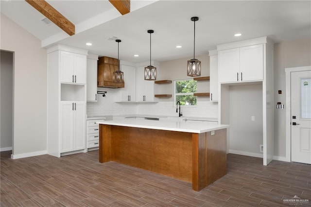 kitchen featuring a center island, dark wood-type flooring, vaulted ceiling with beams, pendant lighting, and white cabinets