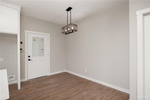 unfurnished dining area with hardwood / wood-style flooring and an inviting chandelier