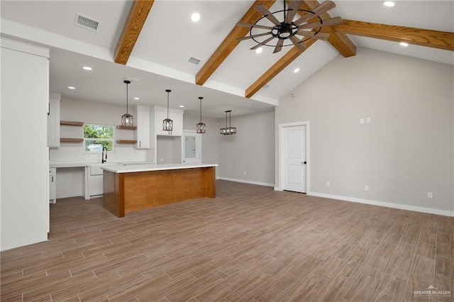 kitchen featuring ceiling fan, a kitchen island, decorative light fixtures, light hardwood / wood-style floors, and white cabinetry