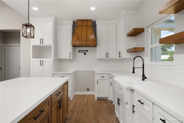 kitchen featuring white cabinets, decorative light fixtures, sink, and backsplash