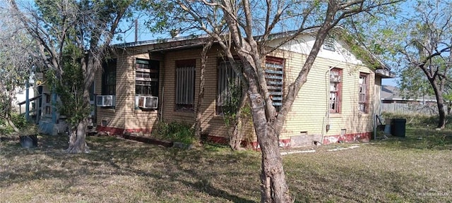 view of side of property featuring cooling unit, crawl space, and a lawn