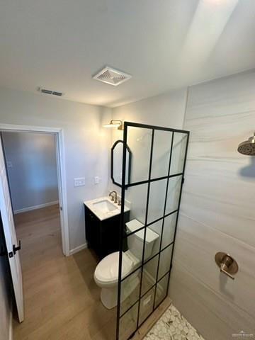 bathroom featuring vanity, hardwood / wood-style flooring, toilet, and walk in shower