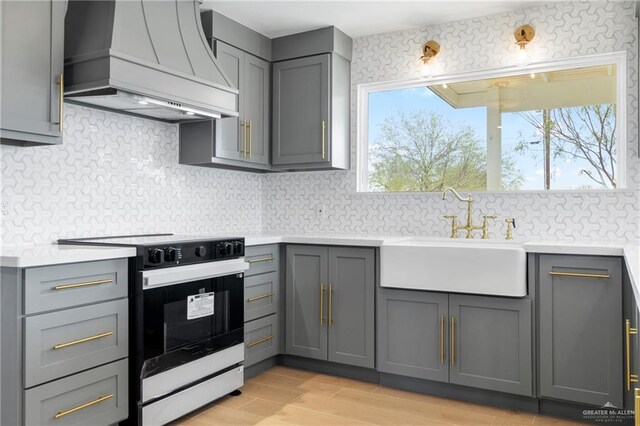 kitchen featuring sink, range, backsplash, pendant lighting, and custom exhaust hood