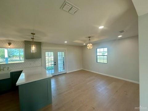 interior space with kitchen peninsula, french doors, tasteful backsplash, hardwood / wood-style flooring, and hanging light fixtures