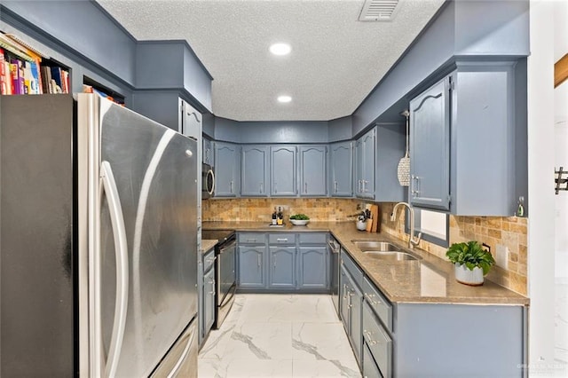 kitchen with a textured ceiling, decorative backsplash, sink, and appliances with stainless steel finishes