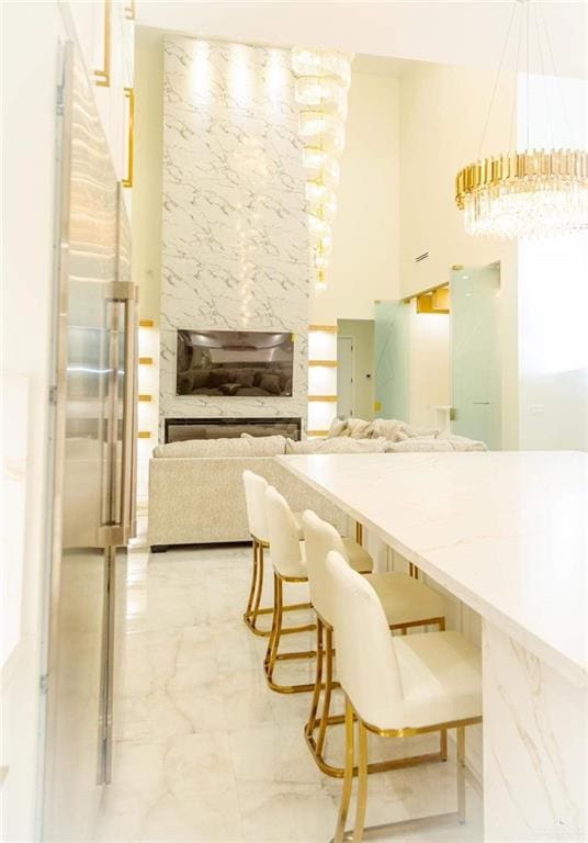 kitchen with a kitchen bar, a chandelier, hanging light fixtures, and a high ceiling