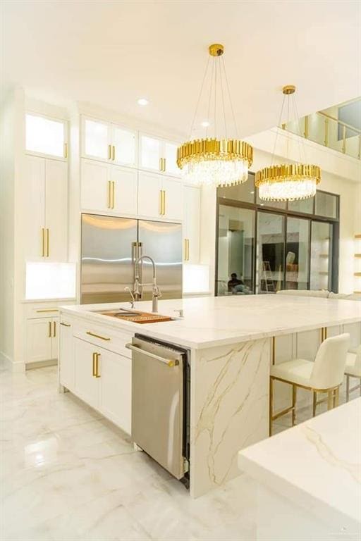 kitchen featuring white cabinetry, a center island with sink, hanging light fixtures, and appliances with stainless steel finishes