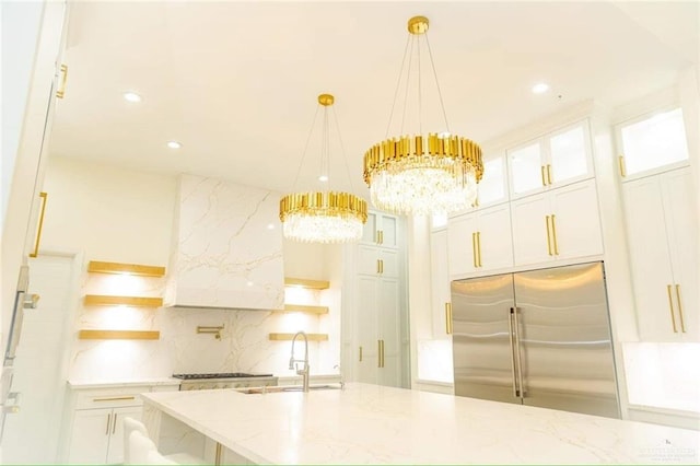 kitchen featuring white cabinetry, light stone countertops, sink, hanging light fixtures, and high quality fridge