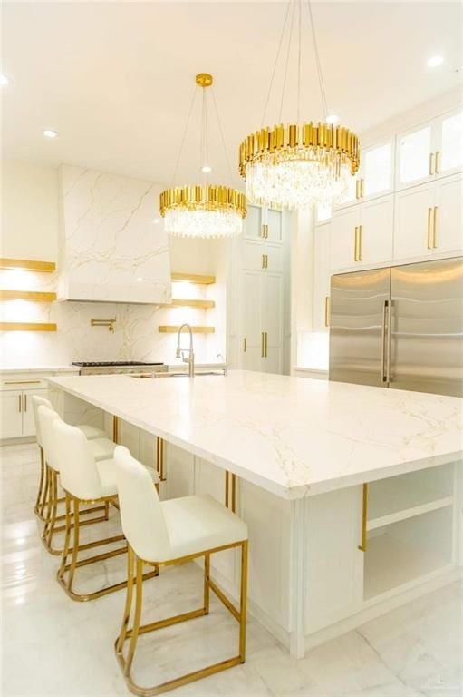 kitchen featuring white cabinets, decorative light fixtures, light stone counters, and sink