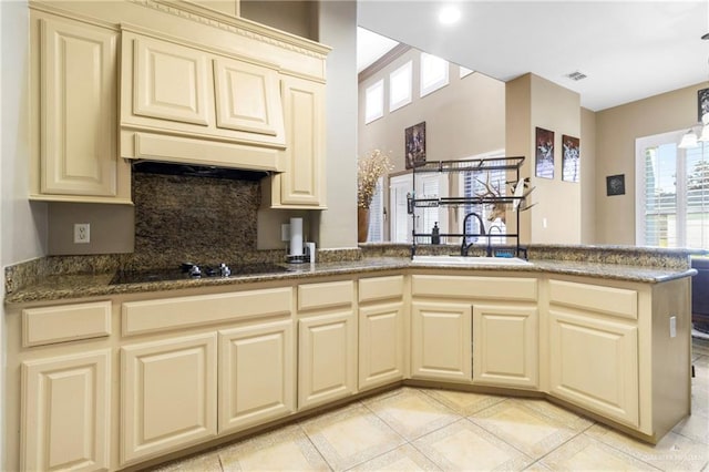 4004 Persimmon Dr, Palmhurst, TX 78573 - kitchen with cream cabinetry, a sink, black electric cooktop, a peninsula, and backsplash