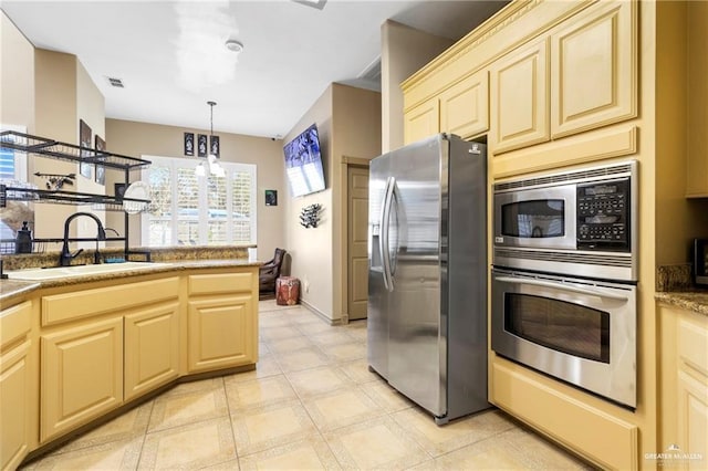 4004 Persimmon Dr, Palmhurst, TX 78573 - kitchen featuring stainless steel appliances, a sink, hanging light fixtures, light flooring, and cream cabinetry