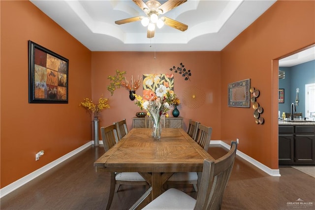 dining room with ceiling fan, sink, and a tray ceiling