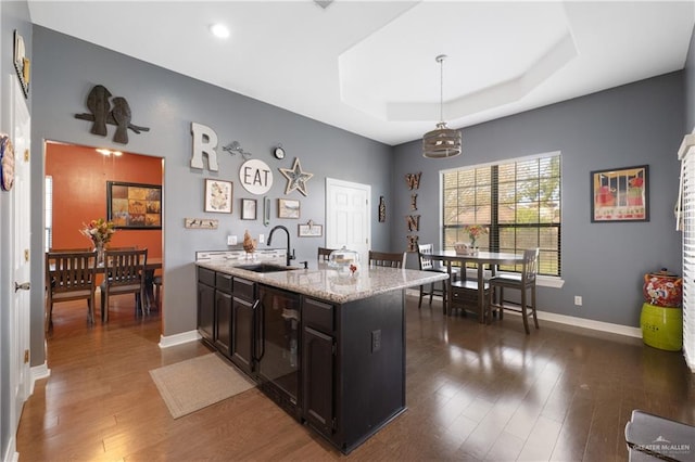 kitchen with pendant lighting, dark hardwood / wood-style floors, a raised ceiling, and sink