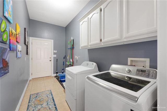 washroom featuring washing machine and dryer, light tile patterned flooring, and cabinets