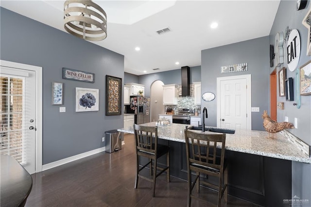 506 Orchard Ct, Weslaco, TX 78596 - kitchen with stainless steel appliances, a peninsula, wall chimney range hood, white cabinets, and a kitchen bar