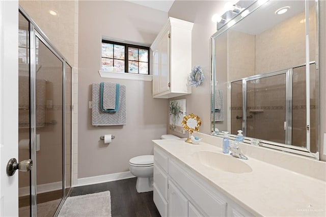 bathroom featuring vanity, toilet, wood-type flooring, and a shower with door