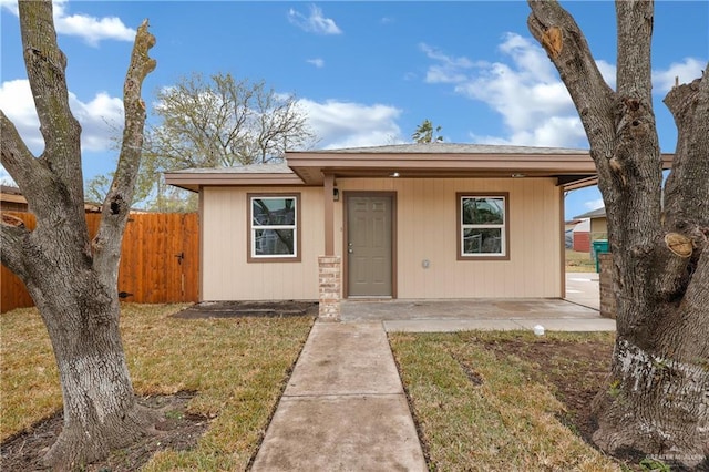 bungalow-style home with a front lawn and fence