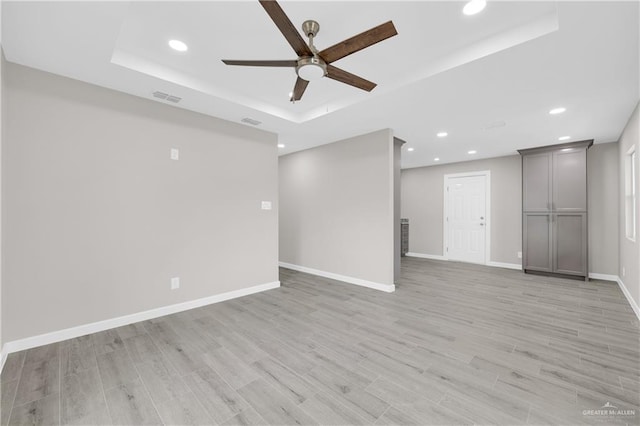 unfurnished room with a raised ceiling, visible vents, baseboards, and light wood finished floors