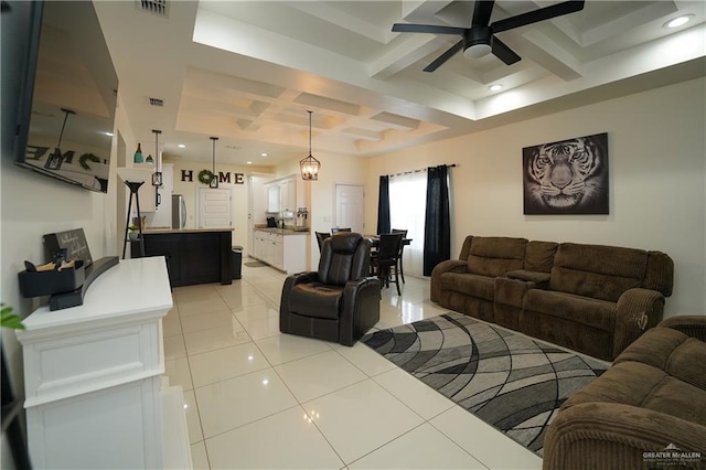 living room featuring coffered ceiling, light tile patterned floors, beamed ceiling, and ceiling fan