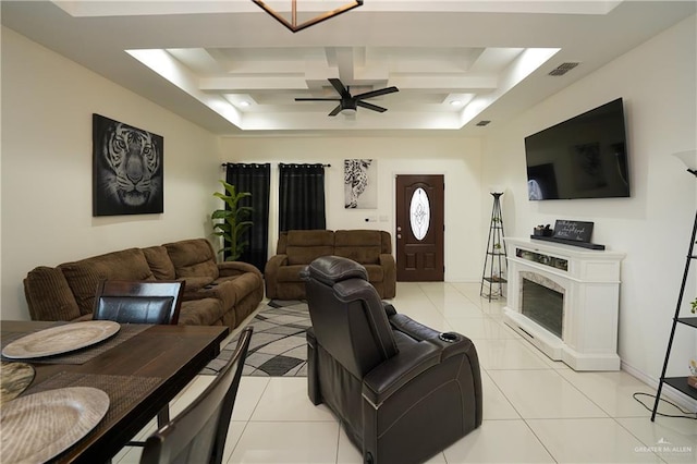 living room featuring light tile patterned flooring, a high end fireplace, ceiling fan, and a tray ceiling